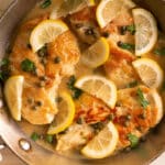 top view of chicken piccata in a pan on top of a wooden table